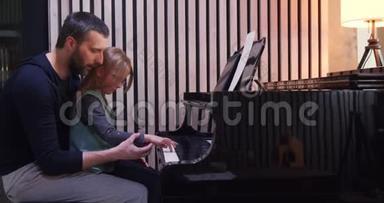 爸爸给女儿教钢琴。 小女孩在家学钢琴。 侧视。 家里的钢琴课。 儿童学习